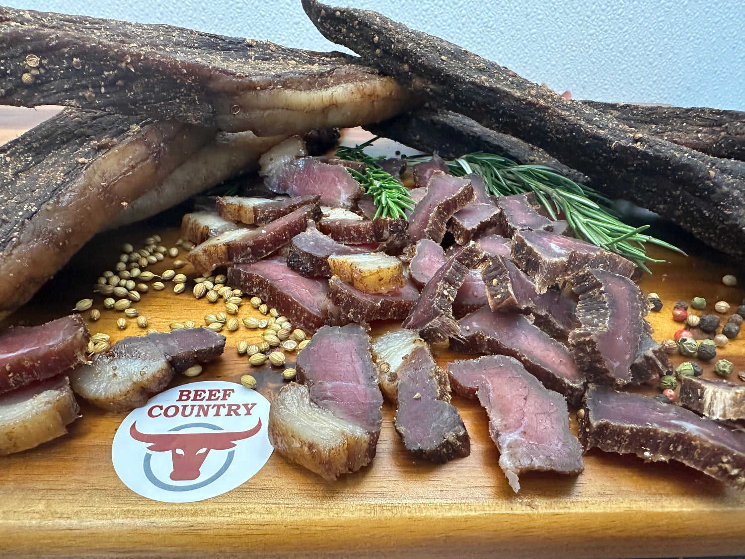 Dried beef slices on a wooden board with spices and a 'Beef Country' logo.